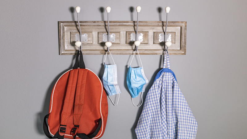 cabide numa escola com uma mochila, máscaras cirúrgicas e um bibe pendurados